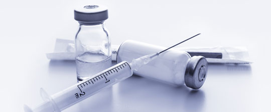 a needle laying on an empty glass vaccine bottle